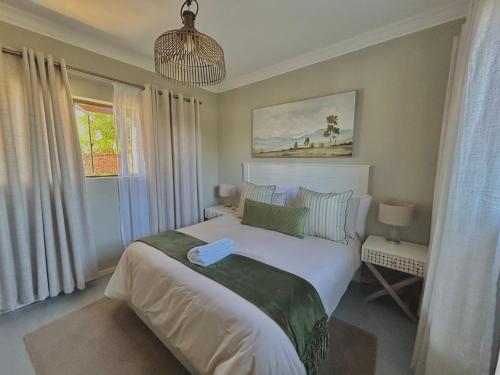 Un dormitorio con una gran cama blanca y una ventana en The Acorn @ Skyfall Country Estate en Polokwane