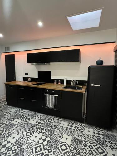 een keuken met een zwarte koelkast en een tegelvloer bij Nid d’Angers - Spa, Sauna privatifs & Écran cinéma in Angers