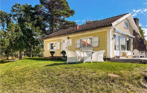 una casa amarilla con sillas blancas en el patio en Nice Home In Frjestaden With House Sea View, en Färjestaden