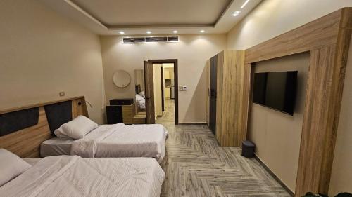 a hotel room with two beds and a flat screen tv at Grand Room in Sheikh Zayed