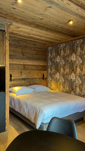 une chambre avec un grand lit avec un mur en bois dans l'établissement Résidence GRAND COCOR, Skis aux pieds -Studio 25 m2- by MONTBLANC LOGDE, à Val dʼIsère