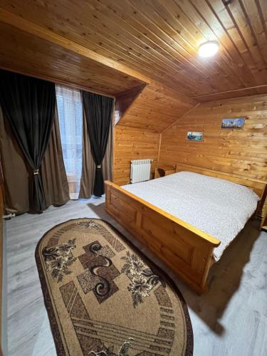 ヤレムチャにあるКотедж "ГІРСЬКА РОСА" Яремче Чан Басейн Саунаの木造キャビン内のベッド1台が備わるベッドルーム1室を利用します。