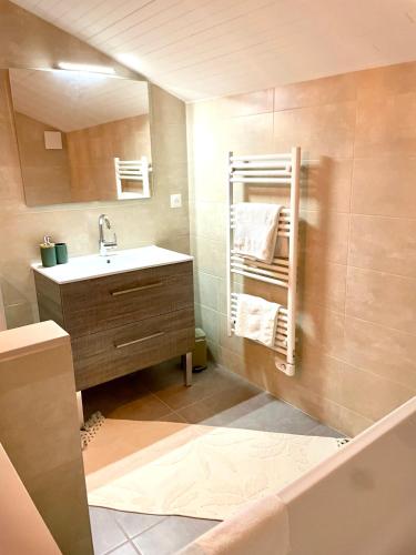 une salle de bain avec un lavabo et un miroir dans l'établissement Maison au coeur de la Dombes, à Le Plantay