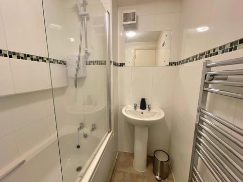 a white bathroom with a sink and a shower at Vibrant Loft Apartment in Grade II Listed Georgian Building in Sheffield