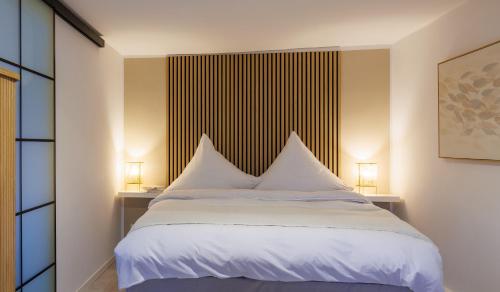 - une chambre avec un lit avec des draps blancs et 2 lampes dans l'établissement Romantisches Apartment mit Whirlpool in Bayreuther Fußgängerzone, à Bayreuth