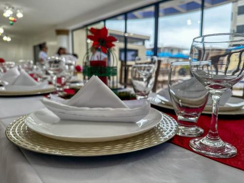 una mesa con platos blancos y copas de vino. en Hotel Bucaneiro, en Manta