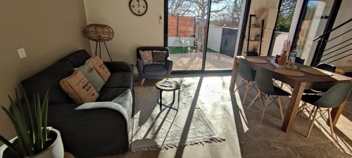 uma sala de estar com um sofá, uma mesa e cadeiras em La maisonnette "Au calme et sans vis à vis" em Canaules-et-Argentières