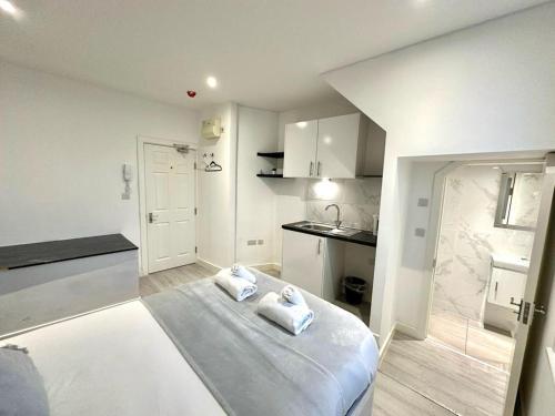 a white room with a bed and a kitchen at Kent House Suites - SE26 in Forest Hill