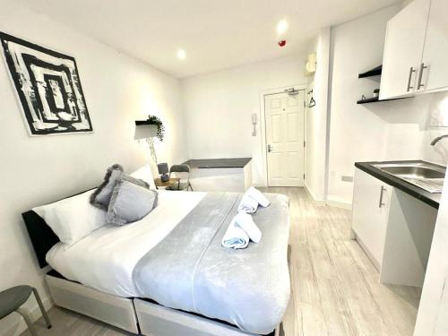 a white bedroom with a large bed and a kitchen at Kent House Suites - SE26 in Forest Hill