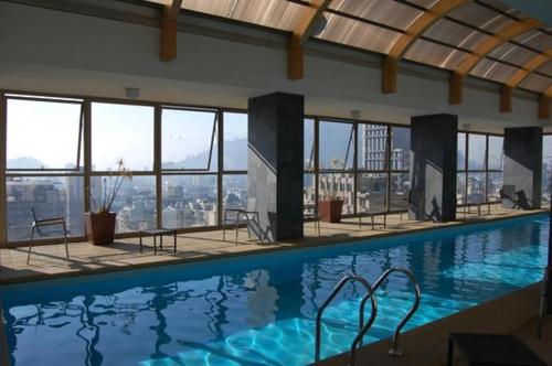 a large swimming pool in a building with windows at Dpto Gran Vista Santiago in Santiago