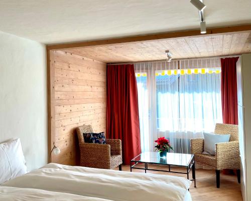 a bedroom with a bed and two chairs and a table at Apartment Gstaaderhof in Gstaad