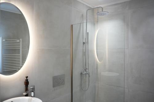a bathroom with a shower with a sink and a mirror at Guesthouse Doma in Arachova