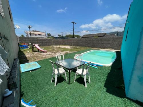 een tafel en stoelen naast een zwembad bij 200m da Praia, Piscina Itanhaém in Itanhaém