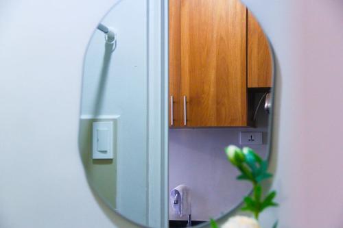 a mirror in a bathroom with a wooden cabinet at The Loop North Tower in Cagayan de Oro