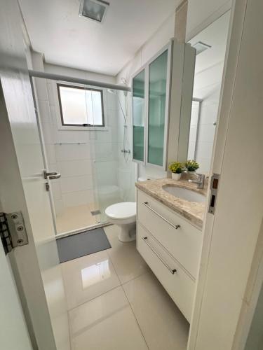a white bathroom with a toilet and a shower at Apartamento 2 quartos a 2 quadras da praia in Capão da Canoa