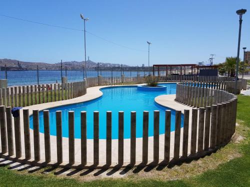 a fence around a swimming pool next to the water at Apartamento junto a la playa en Bahía Horizonte in Coquimbo