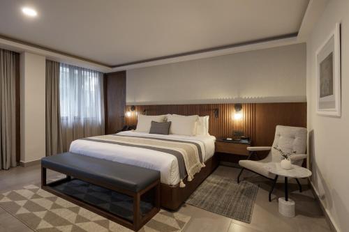 a hotel room with a bed and a chair at Origen 438 Luxury Boutique Hotel in Guadalajara