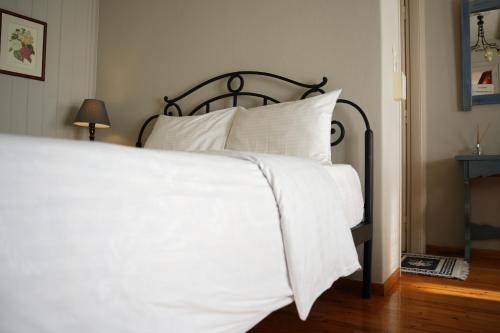 a bed with white sheets and pillows in a bedroom at Guesthouse Doma est 1991 in Arachova
