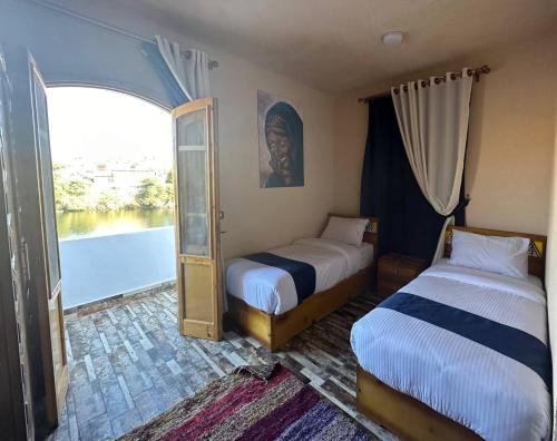 a bedroom with two beds and a window with a view at ACHERTOD NUBIAN HOTEL in Naj‘ al Maḩaţţah