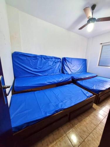 a blue bed in a room with a ceiling at Apartamento para alugar in Mongaguá