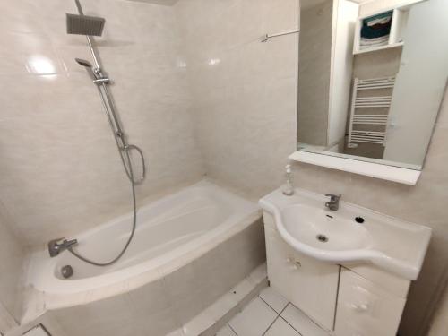 uma casa de banho branca com um chuveiro e um lavatório. em Appartement à côté de Disneyland Paris CK-triomphe em Esbly