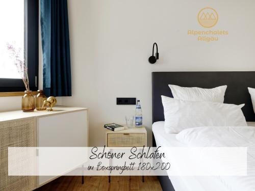 ein Schlafzimmer mit einem weißen Bett und einem Nachttisch in der Unterkunft Hochwertige Alpenchalets Allgäu in Immenstadt im Allgäu