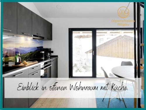 eine Küche mit schwarzen Schränken, einem Tisch und einem Fenster in der Unterkunft Hochwertige Alpenchalets Allgäu in Immenstadt im Allgäu