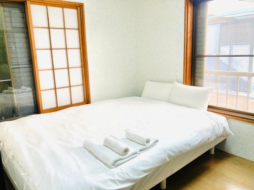 a white bed with two towels on top of it at KIBA HOUSE in Tokyo