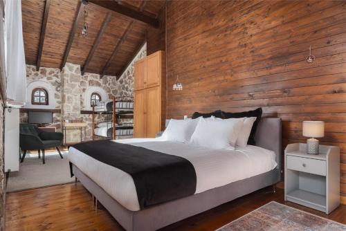 een slaapkamer met een bed met een houten muur bij Parnassus Woodstone Chalet in Áno Polídhrosos