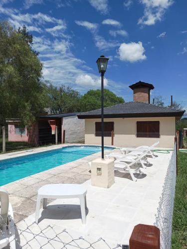 einen Pool mit weißen Liegestühlen und einer hellen Stange in der Unterkunft Casita del Río in Santa Rosa de Calamuchita