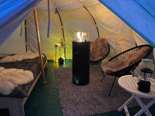 a tent with two chairs and a heater in it at NatureCamp Cuxhaven in Cuxhaven