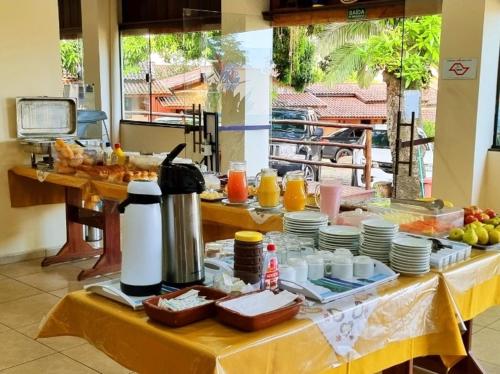 a table with plates and cups on a yellow table cloth at Pousada Recanto Passarela in Aparecida