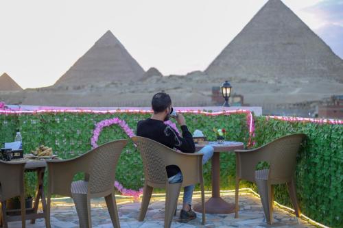 un hombre sentado en una mesa frente a las pirámides en pyramids show hotel en El Cairo