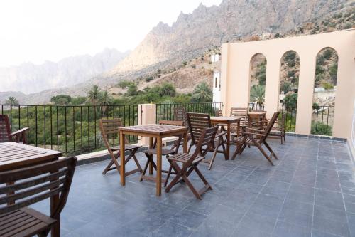 a patio with tables and chairs with mountains in the background at Hadash guest house in Ghubrah