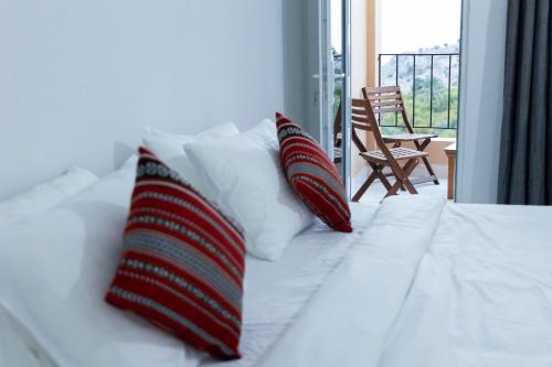 Una cama blanca con dos almohadas rojas y blancas. en Hadash guest house, en Ghubrah