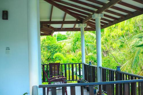 a porch with chairs and a pergola at Bandara House in Midigama