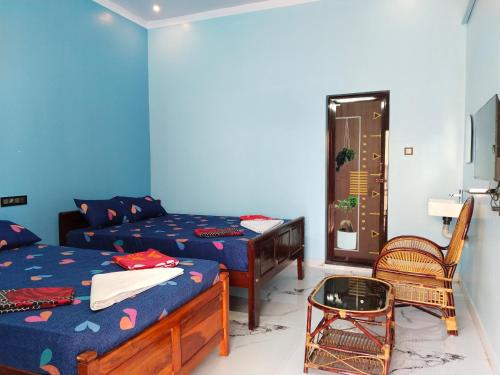 a bedroom with two beds and a table and a chair at Mayurah Illam in Kanyakumari