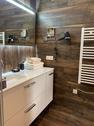 La salle de bains est pourvue de murs en bois et d'un lavabo blanc. dans l'établissement La Cabane D'Ambroise, à Bordeaux