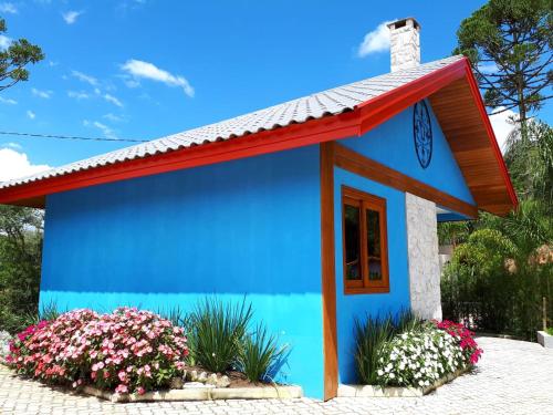 a blue and red house with flowers at Pousada Déllis in Visconde De Maua