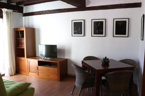 Una sala de estar con una mesa y un televisor. en Sobre Los Tilos Apartamento, en Cuenca