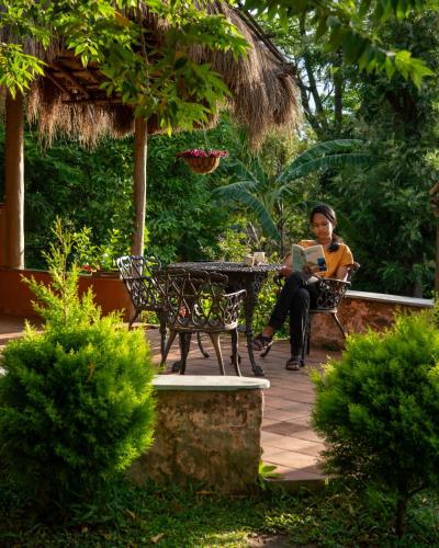 a woman sitting on a bench with a laptop at The Mudhouse Marayoor in Munnar