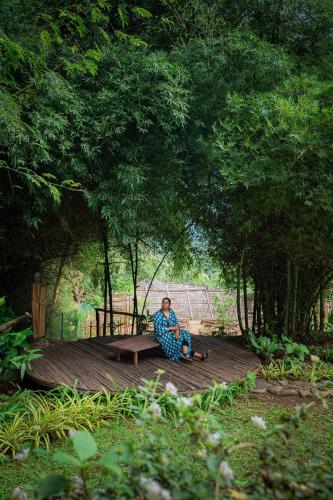 a man sitting on a bench under a tree at The Mudhouse Marayoor in Munnar