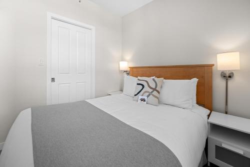 um quarto com uma grande cama branca e uma secretária em Alpenglow Lodge Junior Penthouse by MVA em Whistler