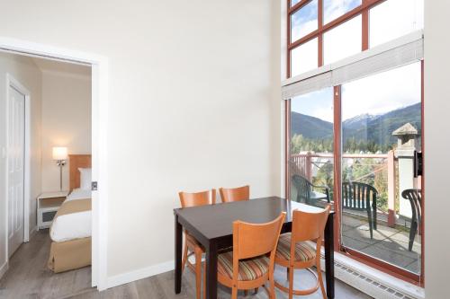 uma sala de jantar com mesa e cadeiras e uma grande janela em Alpenglow Lodge Junior Penthouse by MVA em Whistler
