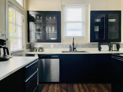 a kitchen with black cabinets and a sink at Abode à la Mode / Centrally Located 2BR/1BA Home in Evansville