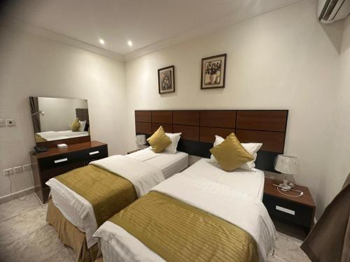 a hotel room with two beds and a mirror at لجين الجوهرة للوحدات المخدومة in Al ‘Azīzīyah