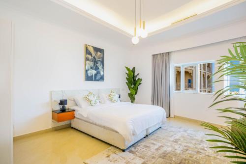 a white bedroom with a bed and a plant at Beautiful Al Marjan sea view Apartment in Ras al Khaimah