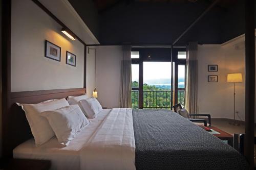 una camera da letto con un grande letto con una grande finestra di Gannoru Hatana Villa a Kandy