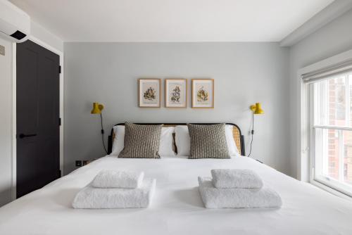 a white bedroom with a large white bed with two pillows at Hausd - Soho in London
