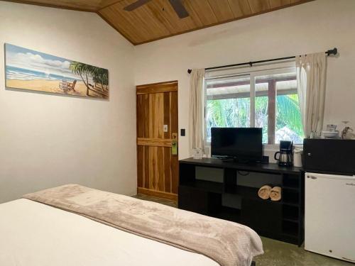 a bedroom with a bed and a desk with a television at Fuego Lodge in Santa Teresa Beach